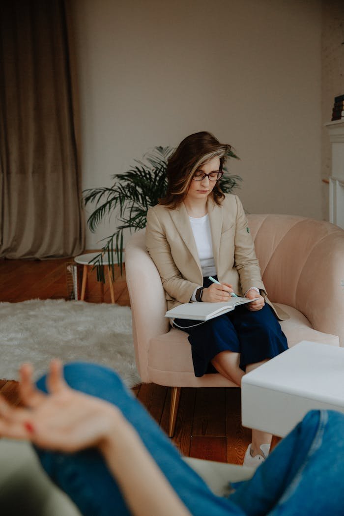 Female therapist writing notes during a counseling session, focusing on mental health.